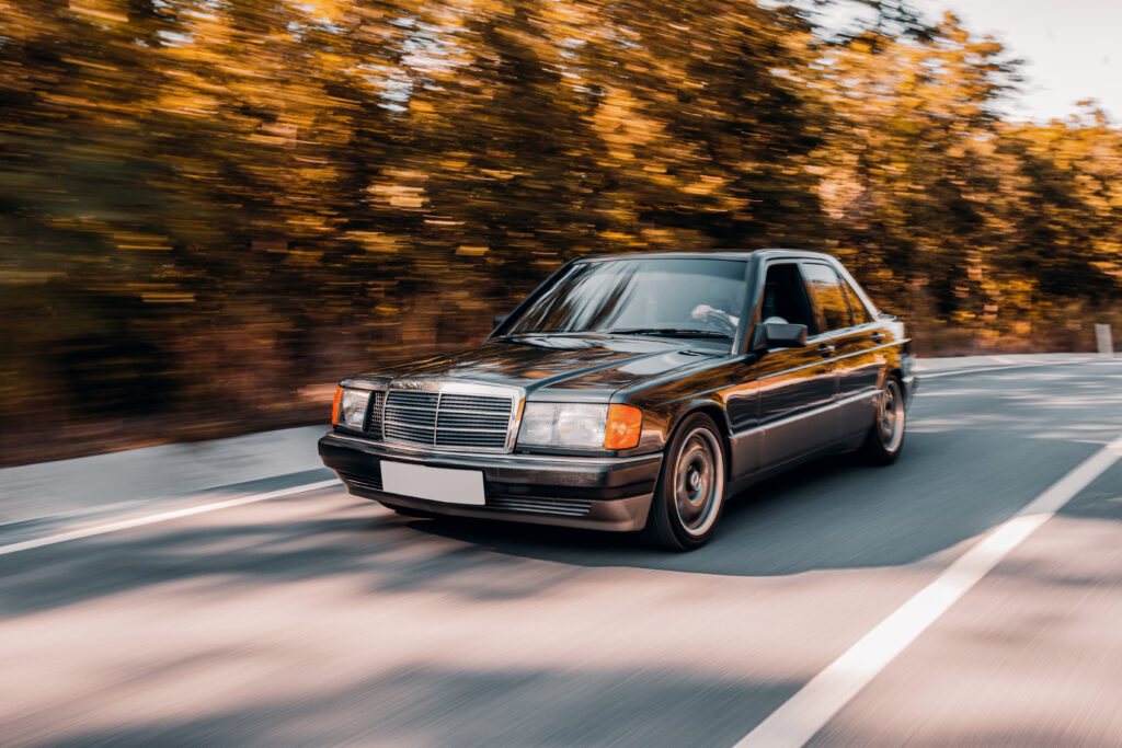 black vintage car driving road longing accross forest